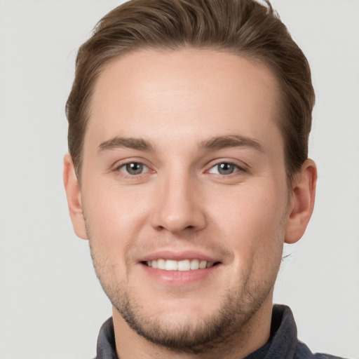 Joyful white young-adult male with short  brown hair and grey eyes