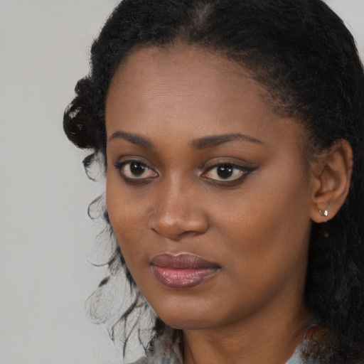 Joyful black young-adult female with long  black hair and brown eyes