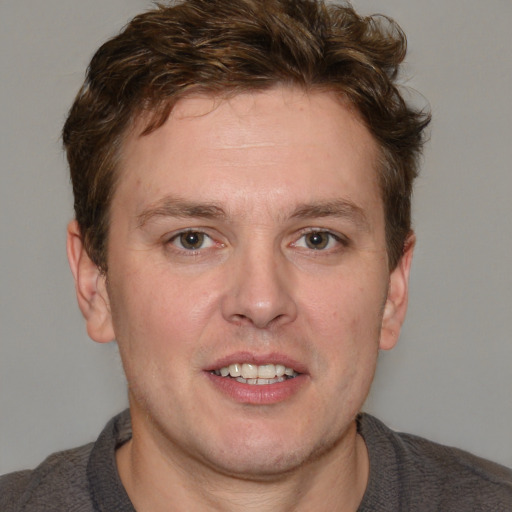 Joyful white adult male with short  brown hair and blue eyes