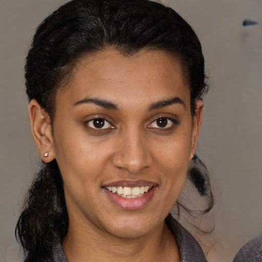 Joyful black young-adult female with medium  brown hair and brown eyes