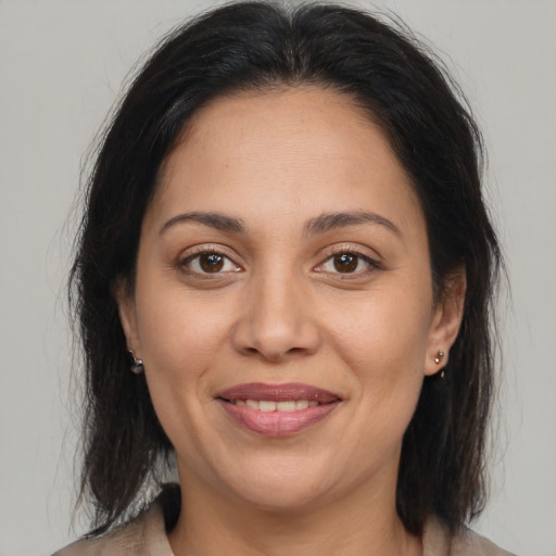 Joyful latino adult female with medium  brown hair and brown eyes