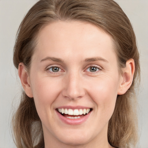 Joyful white young-adult female with medium  brown hair and grey eyes