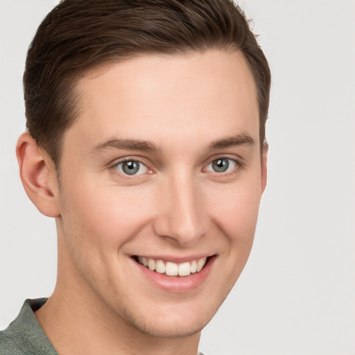 Joyful white young-adult male with short  brown hair and grey eyes