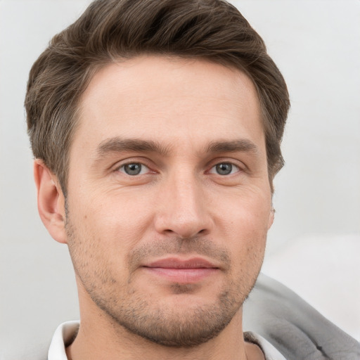 Joyful white young-adult male with short  brown hair and grey eyes