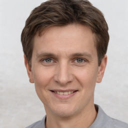 Joyful white young-adult male with short  brown hair and grey eyes