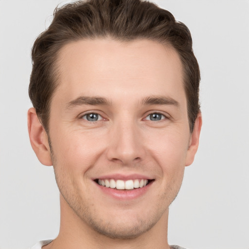 Joyful white young-adult male with short  brown hair and grey eyes