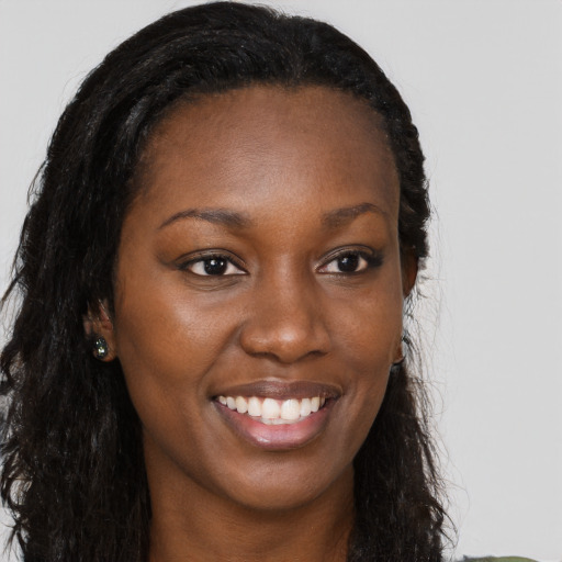 Joyful black young-adult female with long  brown hair and brown eyes