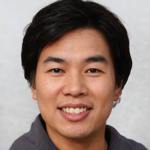 Joyful asian young-adult male with short  brown hair and brown eyes