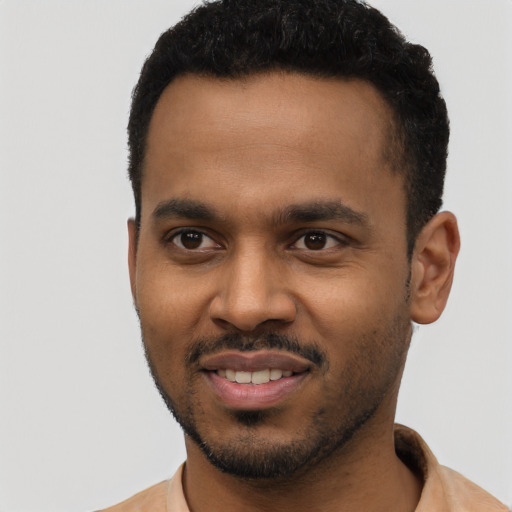 Joyful black young-adult male with short  black hair and brown eyes