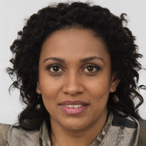 Joyful black young-adult female with long  brown hair and brown eyes