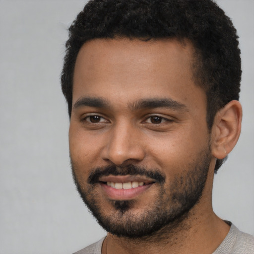 Joyful black young-adult male with short  black hair and brown eyes