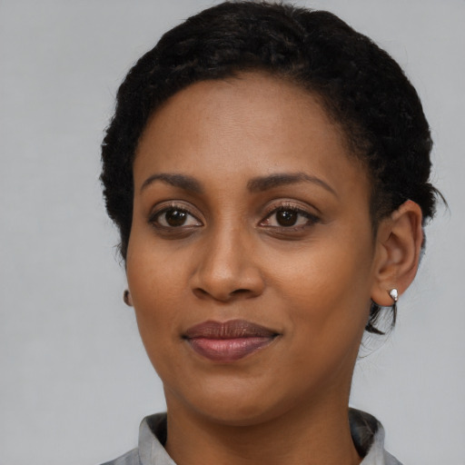Joyful black young-adult female with short  black hair and brown eyes