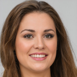 Joyful white young-adult female with long  brown hair and green eyes