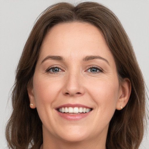 Joyful white adult female with long  brown hair and grey eyes