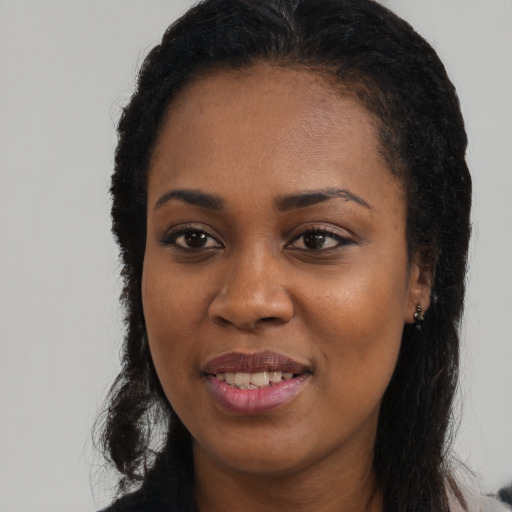 Joyful black young-adult female with long  black hair and brown eyes