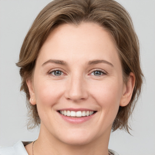 Joyful white young-adult female with medium  brown hair and grey eyes