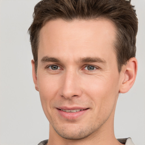 Joyful white young-adult male with short  brown hair and grey eyes