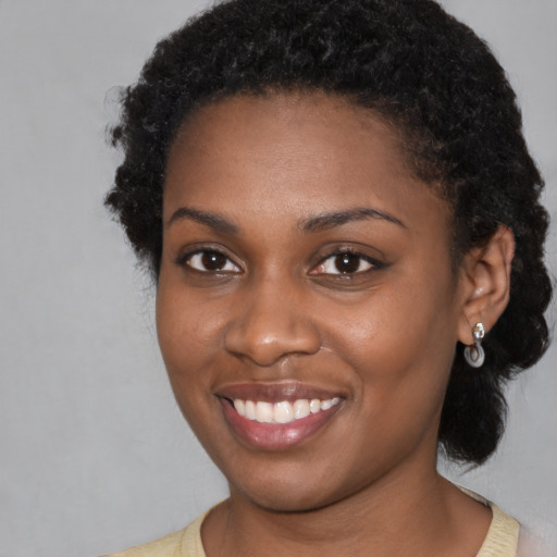 Joyful black young-adult female with short  brown hair and brown eyes