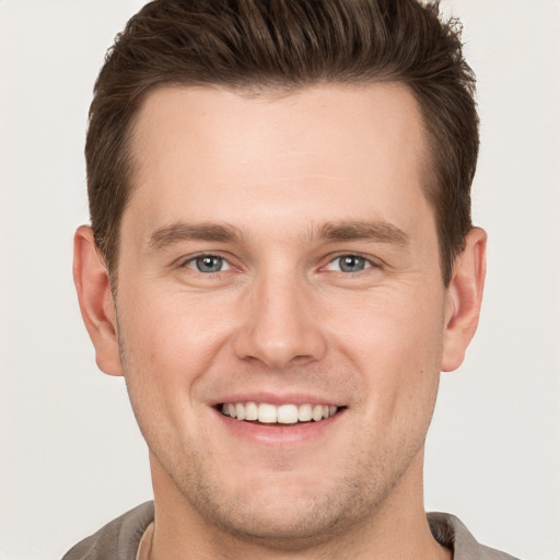 Joyful white young-adult male with short  brown hair and grey eyes