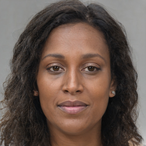 Joyful black young-adult female with long  brown hair and brown eyes