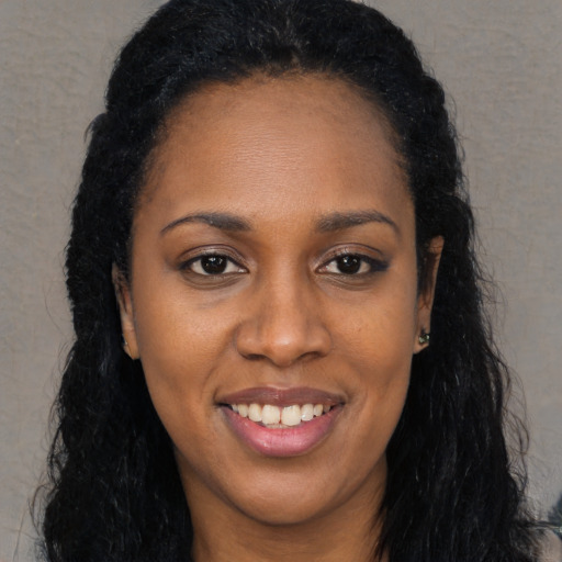 Joyful black young-adult female with long  brown hair and brown eyes