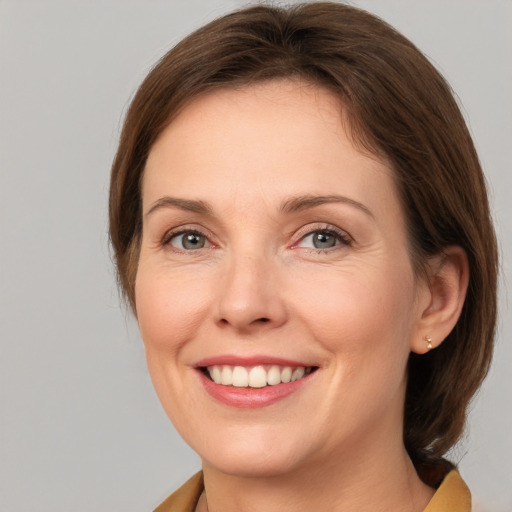 Joyful white young-adult female with medium  brown hair and grey eyes