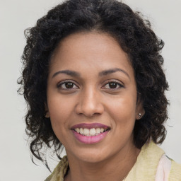 Joyful black young-adult female with long  brown hair and brown eyes