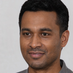 Joyful latino young-adult male with short  black hair and brown eyes