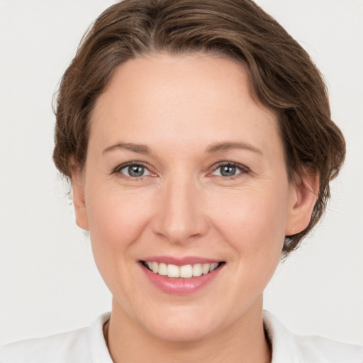 Joyful white young-adult female with medium  brown hair and grey eyes