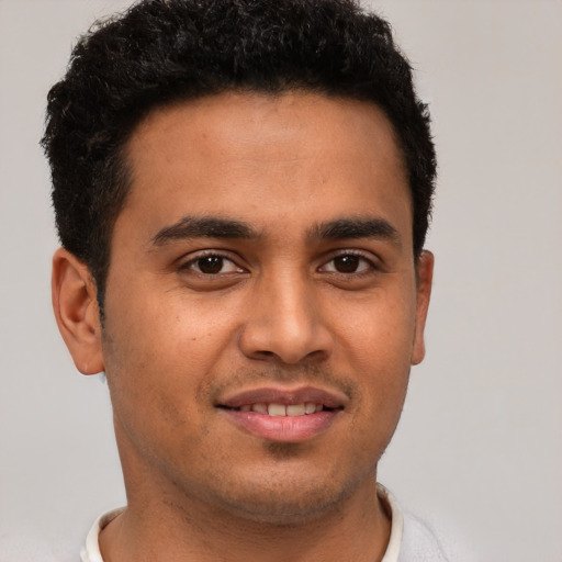 Joyful latino young-adult male with short  brown hair and brown eyes