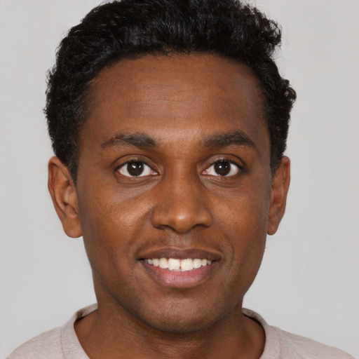 Joyful black young-adult male with short  black hair and brown eyes