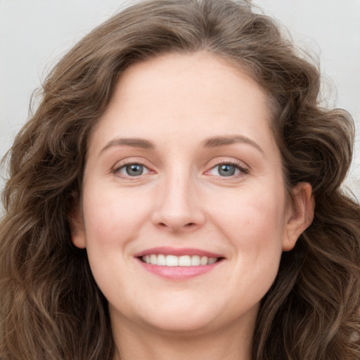 Joyful white young-adult female with long  brown hair and blue eyes