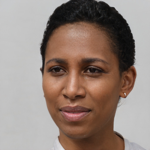 Joyful black young-adult female with short  black hair and brown eyes