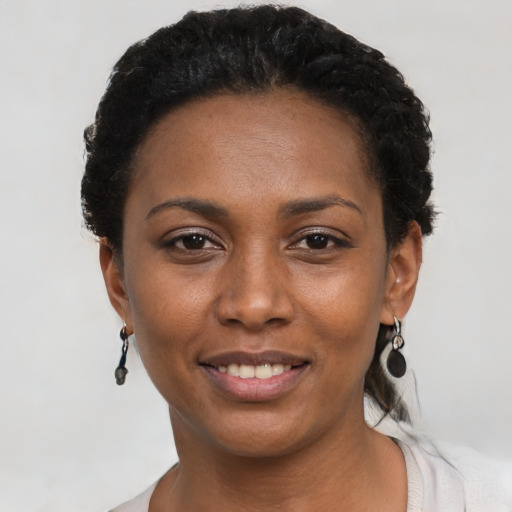 Joyful black young-adult female with short  black hair and brown eyes