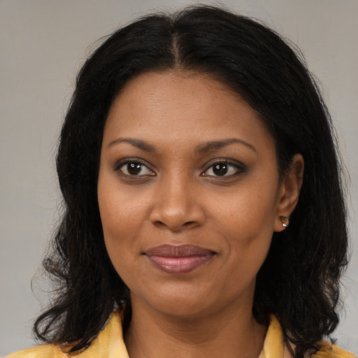 Joyful black young-adult female with long  brown hair and brown eyes