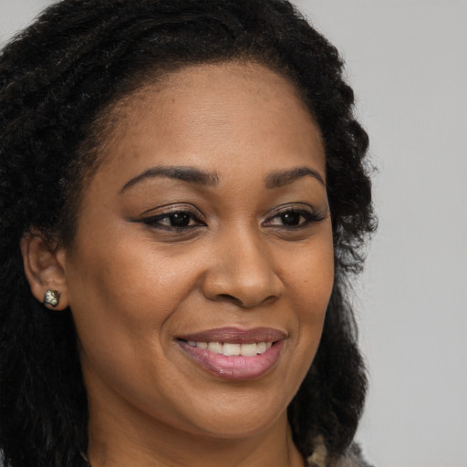Joyful black young-adult female with long  brown hair and brown eyes
