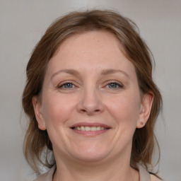 Joyful white adult female with medium  brown hair and blue eyes