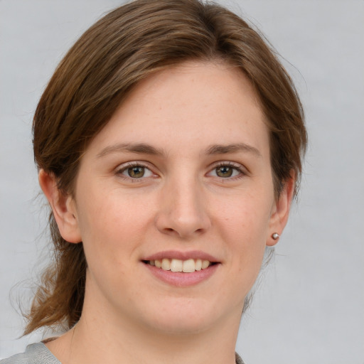 Joyful white young-adult female with medium  brown hair and grey eyes