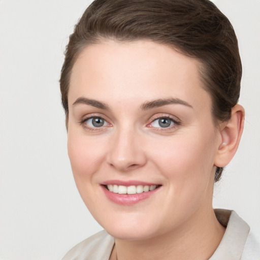 Joyful white young-adult female with short  brown hair and grey eyes