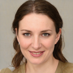 Joyful white young-adult female with medium  brown hair and green eyes