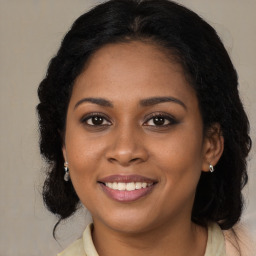 Joyful black young-adult female with long  brown hair and brown eyes