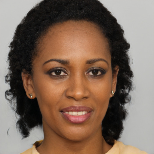Joyful black young-adult female with long  brown hair and brown eyes