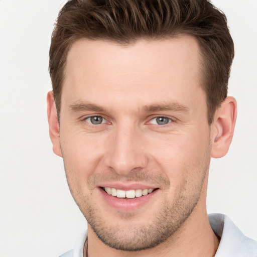 Joyful white young-adult male with short  brown hair and grey eyes