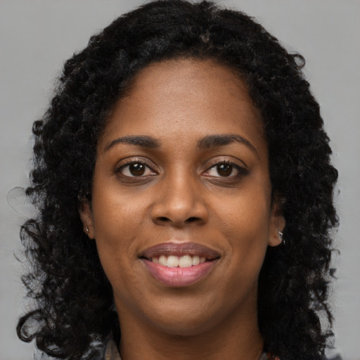 Joyful black young-adult female with long  black hair and brown eyes