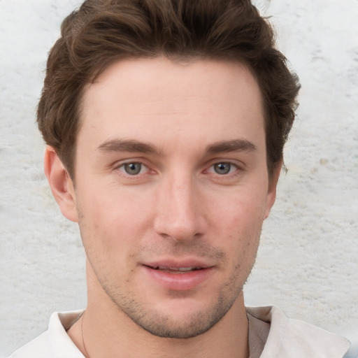 Joyful white young-adult male with short  brown hair and grey eyes