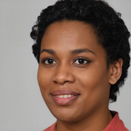 Joyful black young-adult female with short  black hair and brown eyes