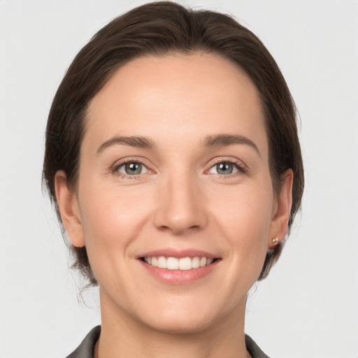 Joyful white young-adult female with medium  brown hair and grey eyes