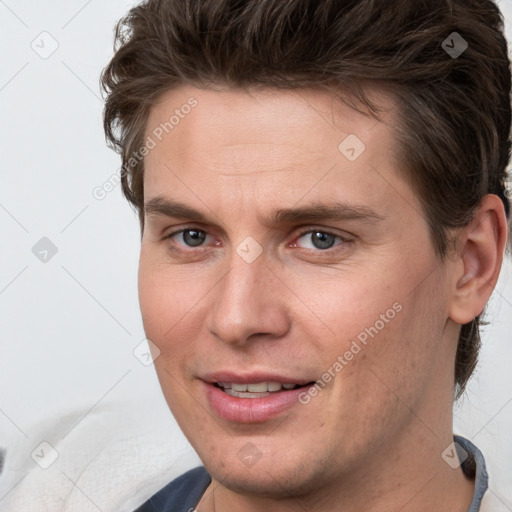 Joyful white young-adult male with short  brown hair and grey eyes