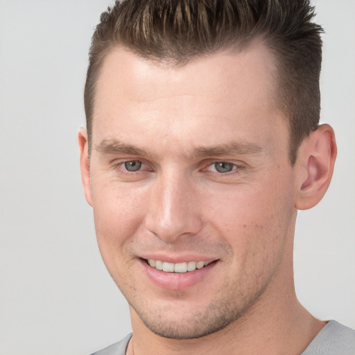 Joyful white young-adult male with short  brown hair and grey eyes