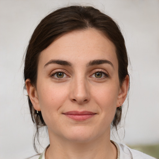 Joyful white young-adult female with medium  brown hair and green eyes